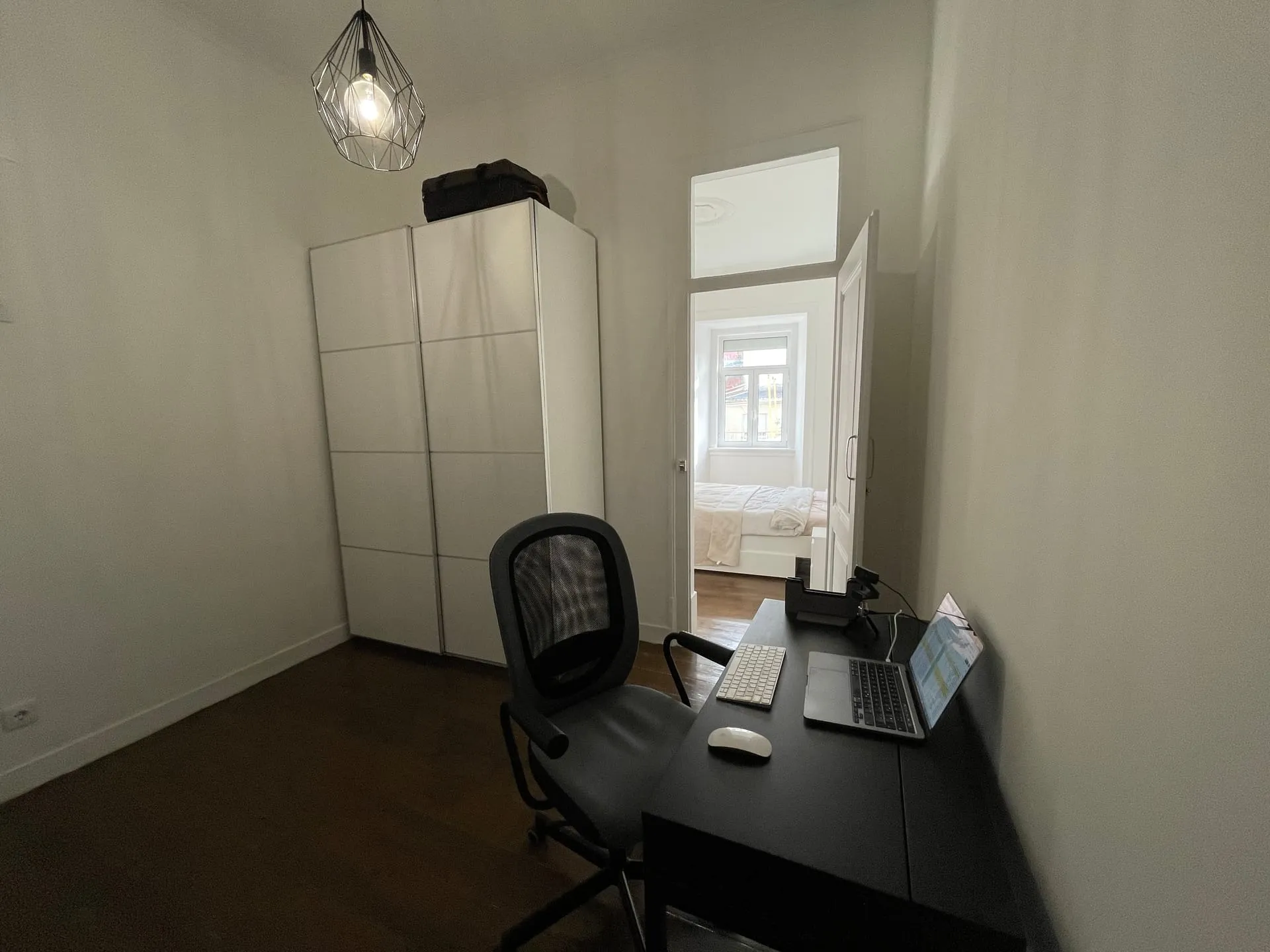 Domowe biuro w lizbońskim apartamencie — biurko z laptopem i widok na sypialnię