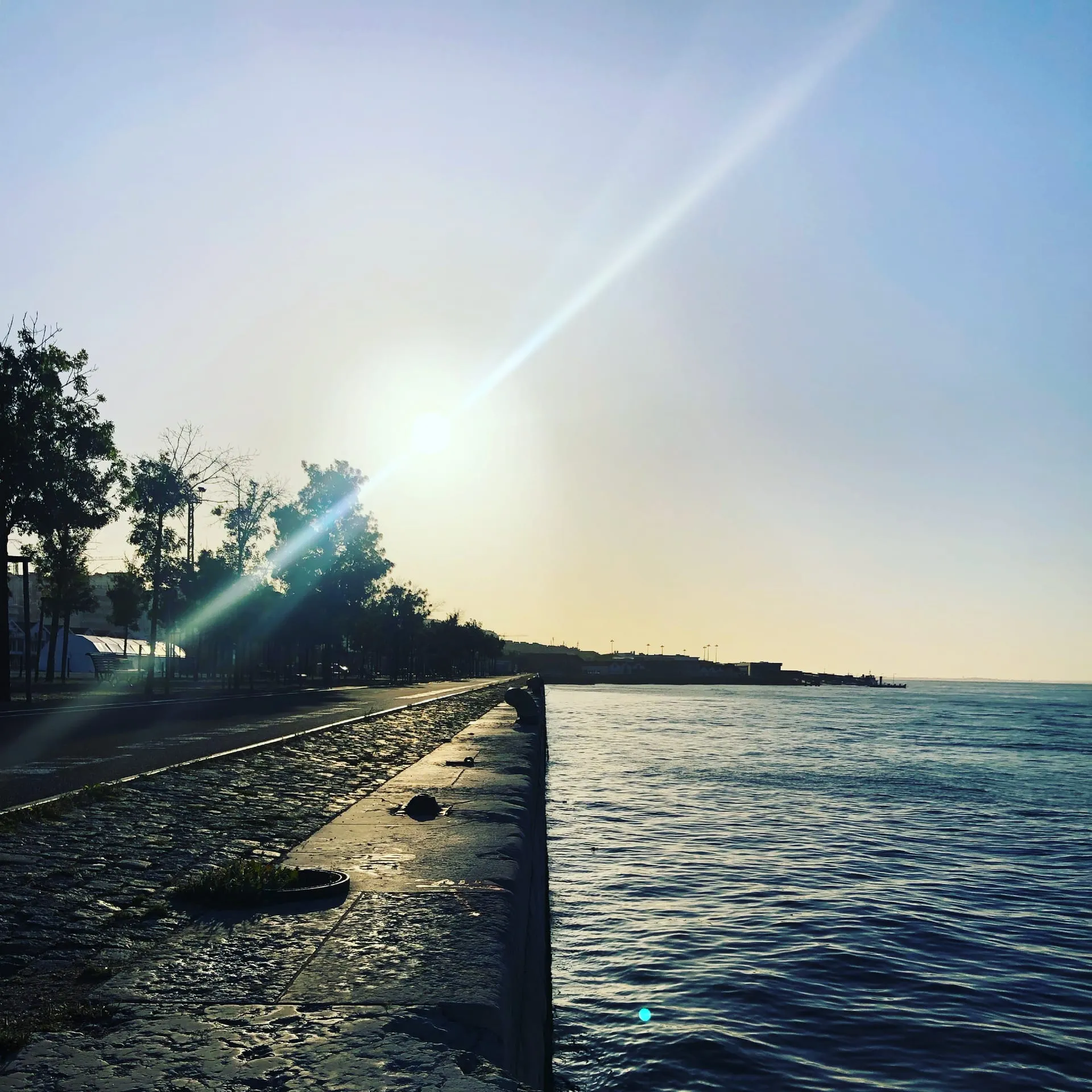 Nabrzeże Tejo o zachodzie słońca — brukowany bulwar, słoneczne refleksy na wodzie