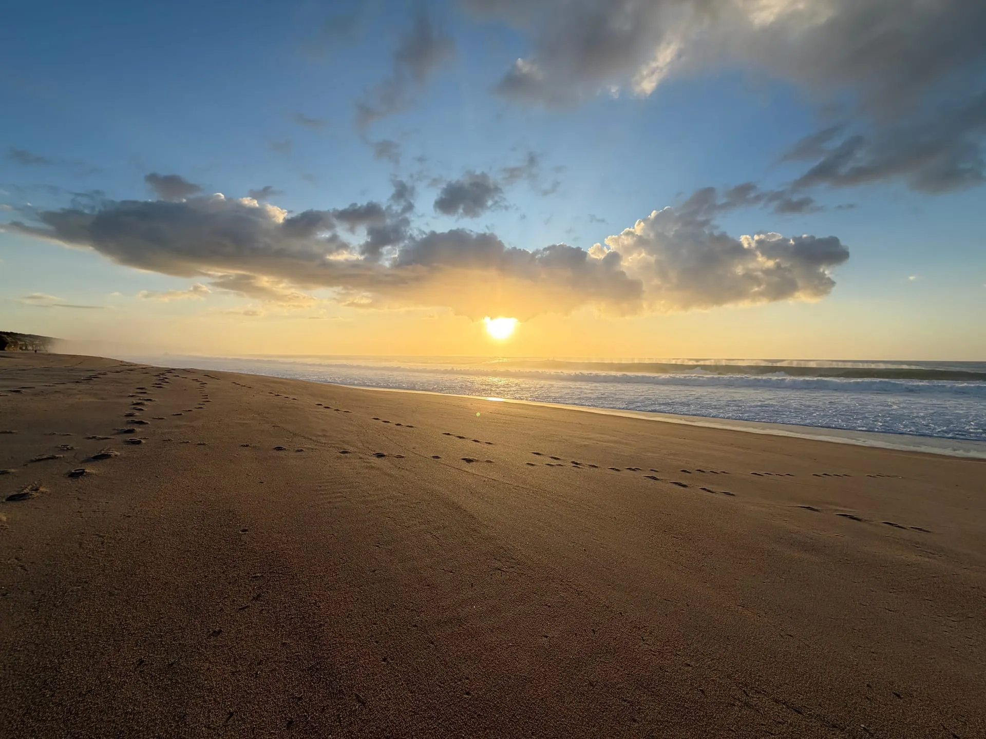 Dzika plaża o zachodzie słońca — złote światło, fale i piasek