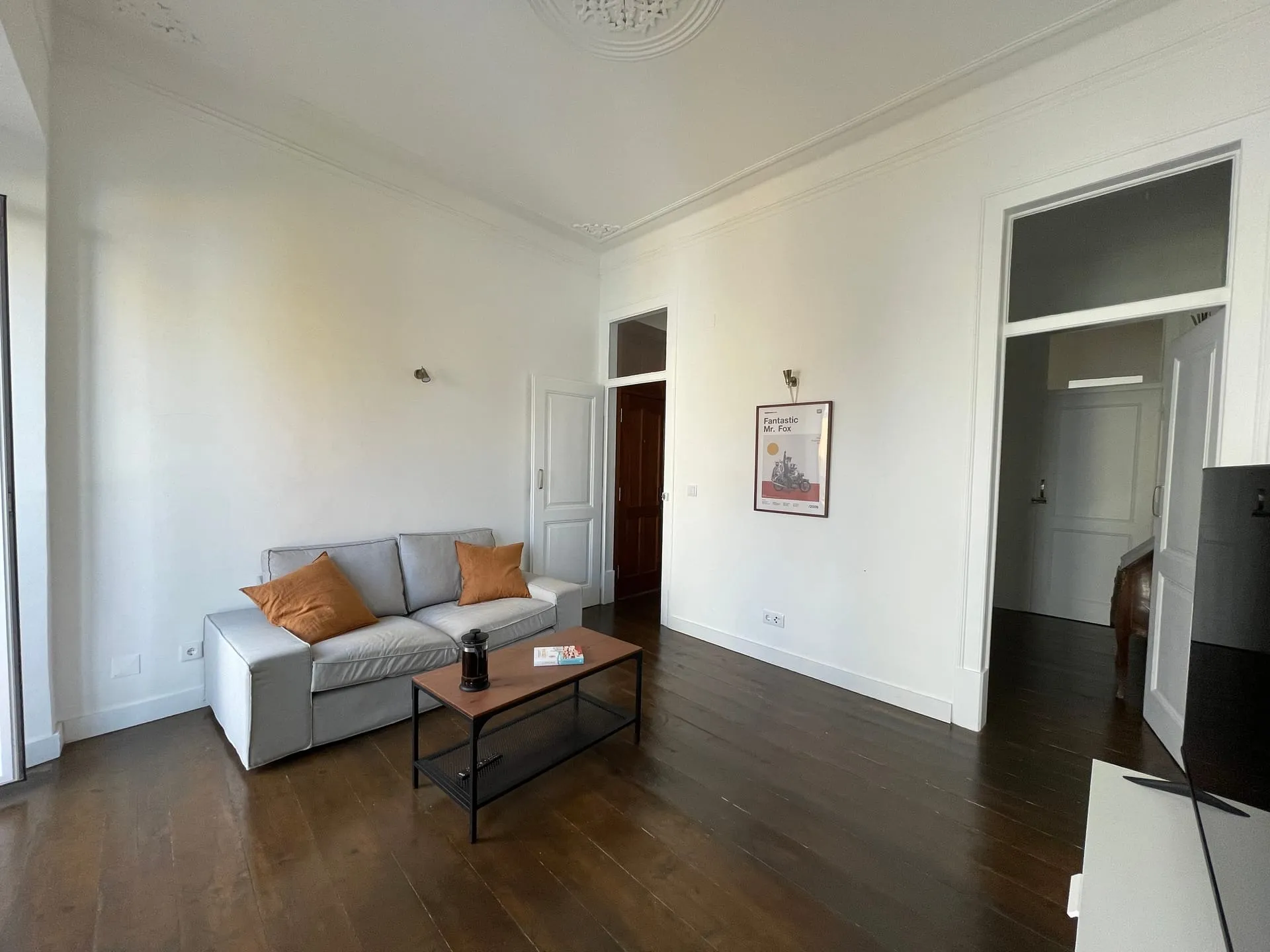 Przestronny salon w wyremontowanym apartamencie w Lizbonie — sztukateria, ciemne drewniane podłogi