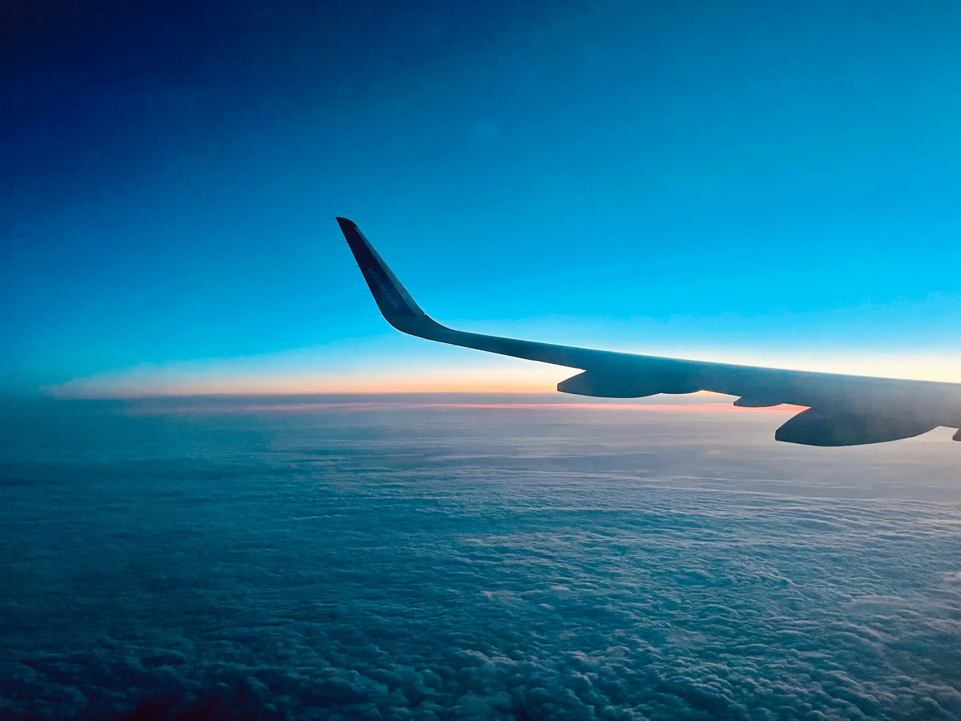 Widok z okna samolotu o zmierzchu — skrzydło nad warstwą chmur