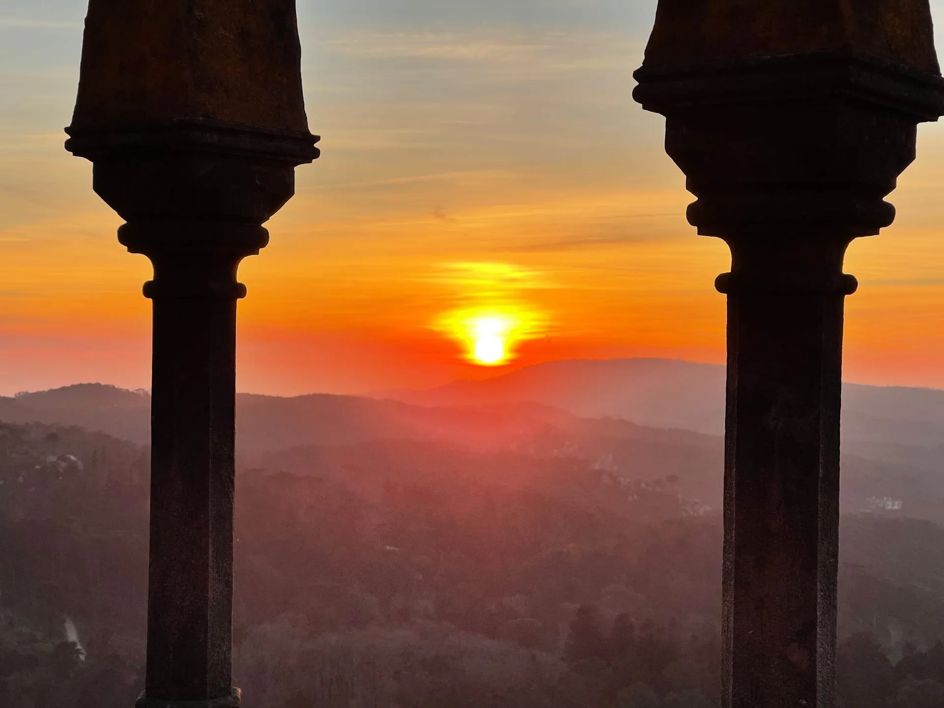 Zachód słońca przez kolumny Pałacu Pena w Sintrze