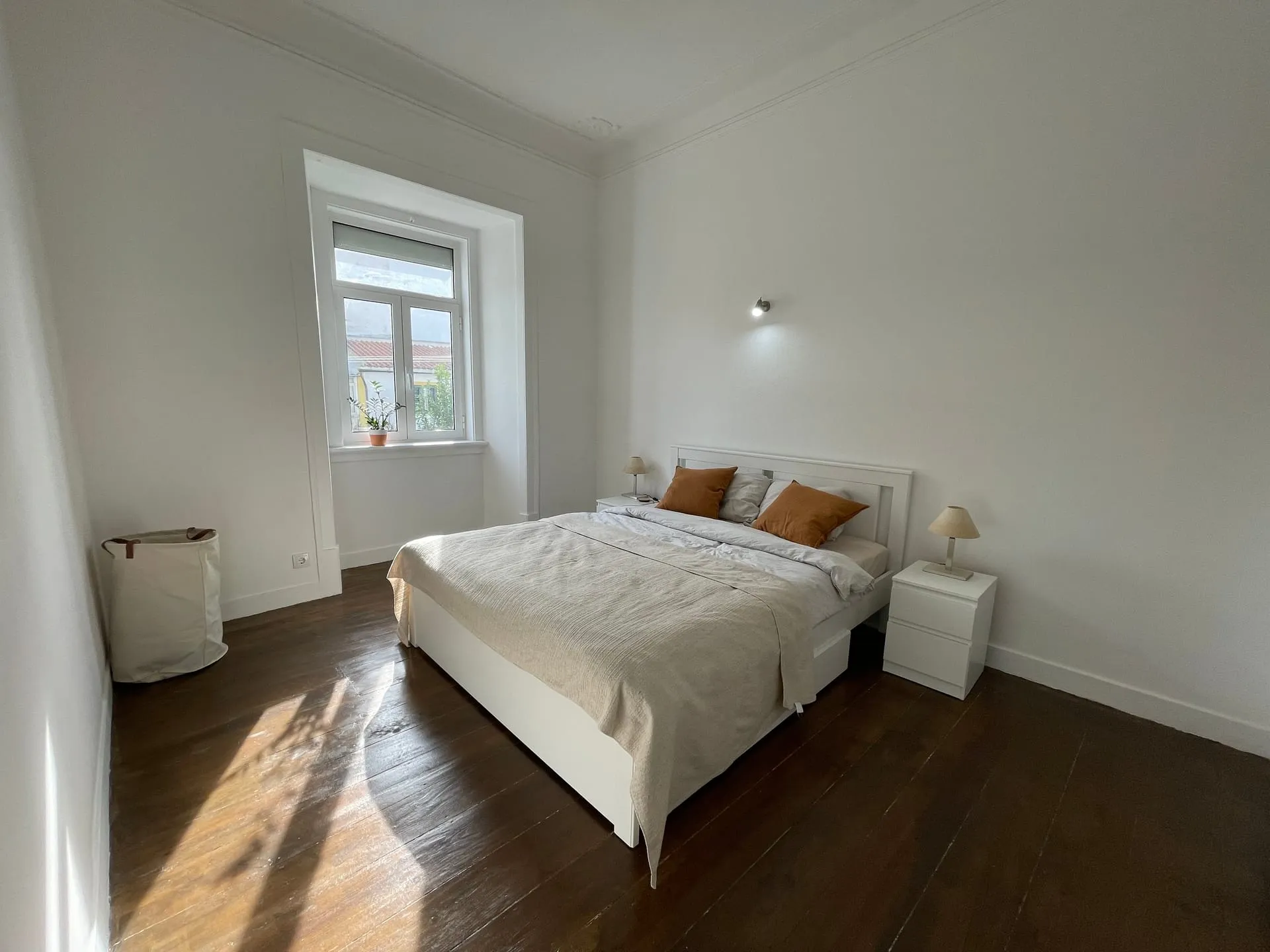 Jasna sypialnia w wyremontowanym apartamencie w Lizbonie — słońce wpada przez okno