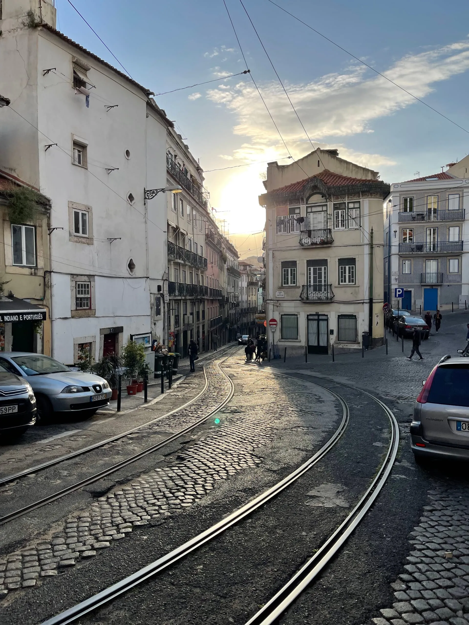 Wąska ulica Lizbony z torami tramwajowymi w kontrze słonecznej